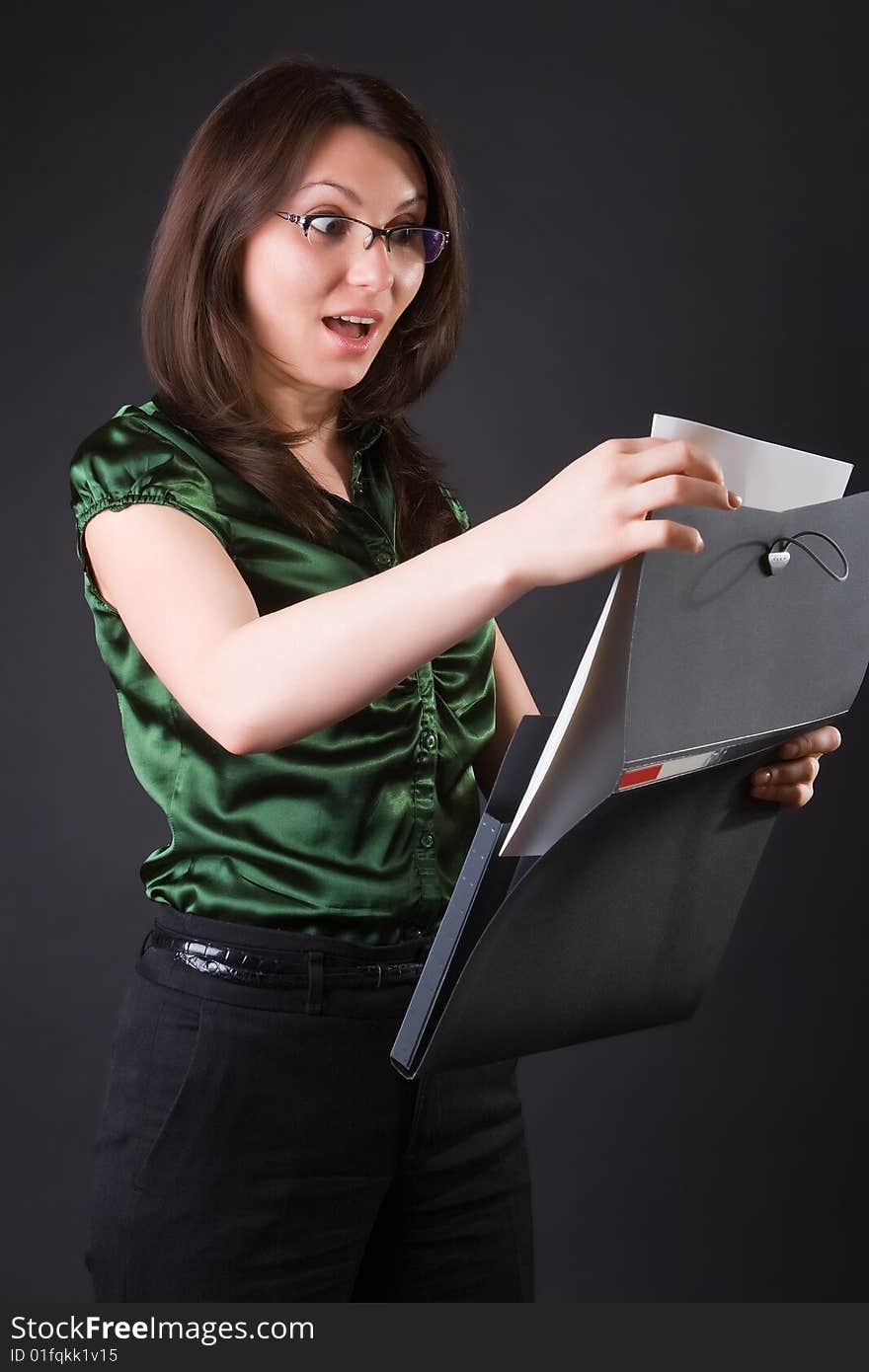 Surprised business woman with a black folder against a dark background