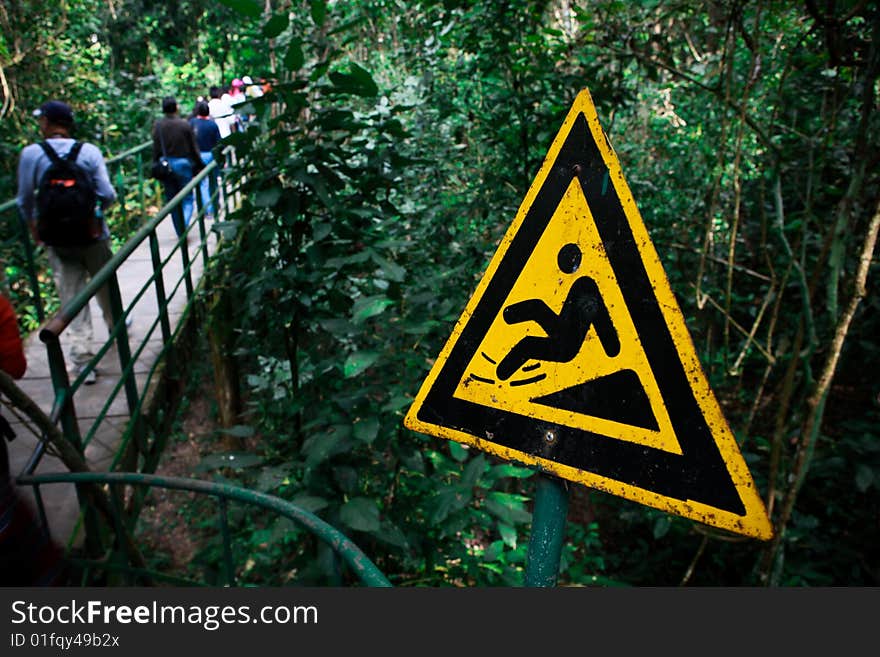 A rust sign warning travellers to avoid flip on bamboo bridge in virgin forests,Xishuangbanna,Yunnan,China. A rust sign warning travellers to avoid flip on bamboo bridge in virgin forests,Xishuangbanna,Yunnan,China