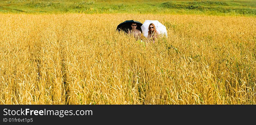 Hot summer. Two people under umbrella on the field