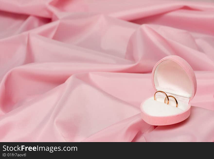 Wedding rings on background of the pink silk.