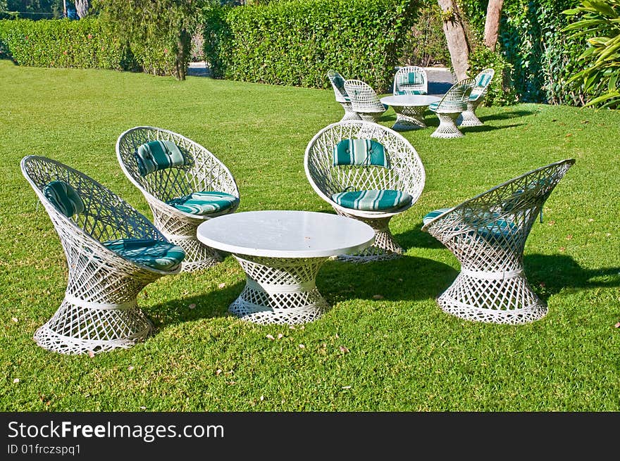 Groups of white cane chairs and table in morning sun. Groups of white cane chairs and table in morning sun