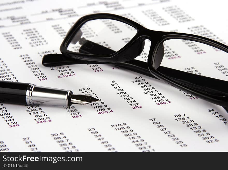 A Financial statement with eyeglasses and fountain pen.