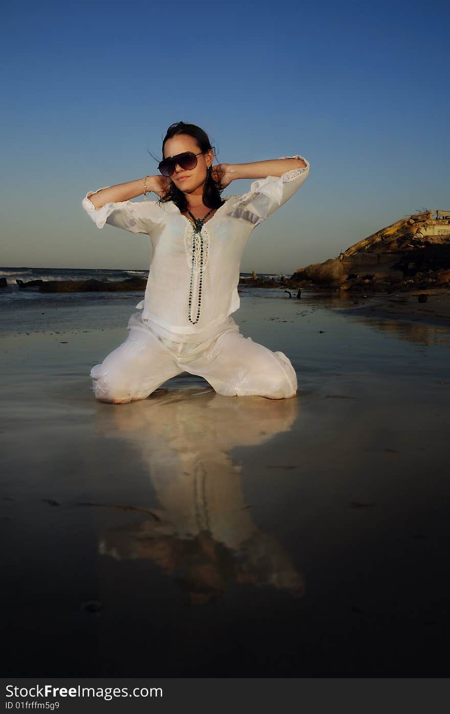 Portrait of young female fashion model posing on the beach at sunset. Portrait of young female fashion model posing on the beach at sunset