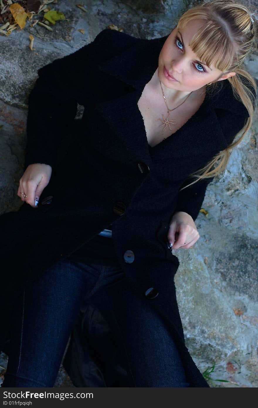 Beautiful young woman lies on the stairs in a black overcoat