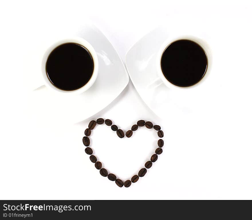 Heart made of coffee beans and two cup of coffee isolated at the white background