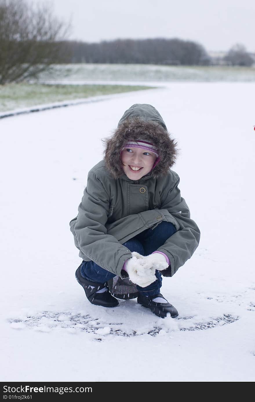 Young mischievous looking girl making a snowball