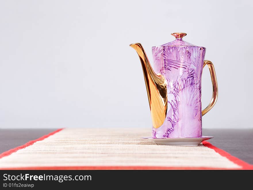 Teapot on the table over grey background