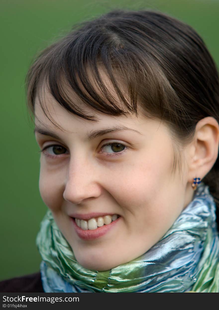 Face portrait of pretty smiling girl on green blurry background