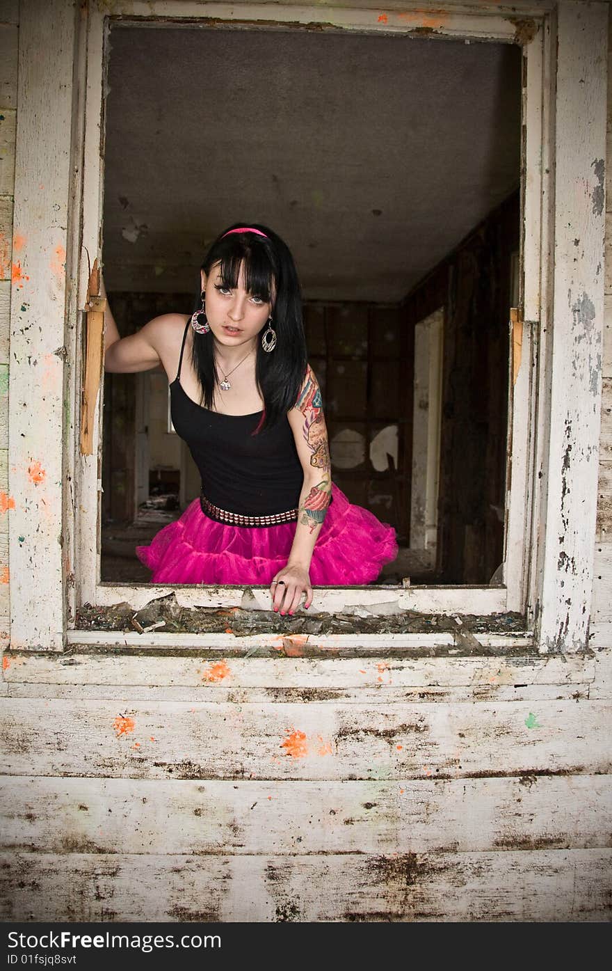 Pretty young woman standing by a window in an abandoned building