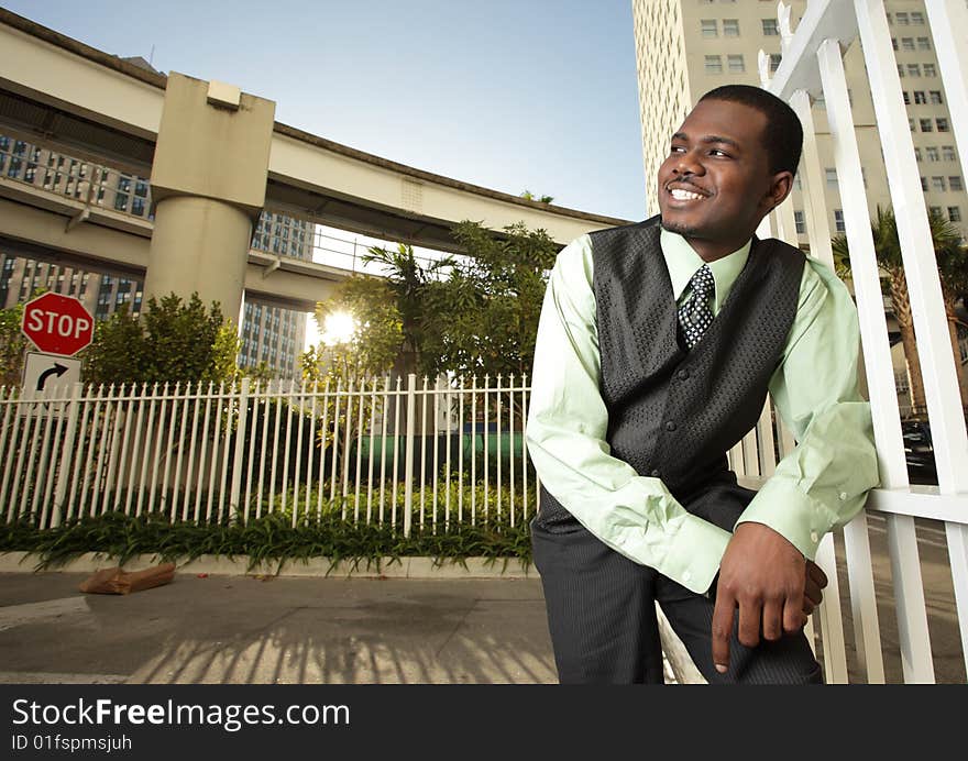 Man in a urban setting smiling while leaning on a fence. Man in a urban setting smiling while leaning on a fence