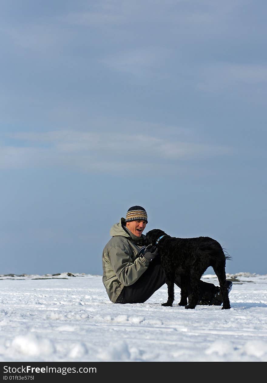 A Portuguese Water Dog retrieves a frisbee for his owner on the frozen shore of Georgian Bay, Ontario. A Portuguese Water Dog retrieves a frisbee for his owner on the frozen shore of Georgian Bay, Ontario