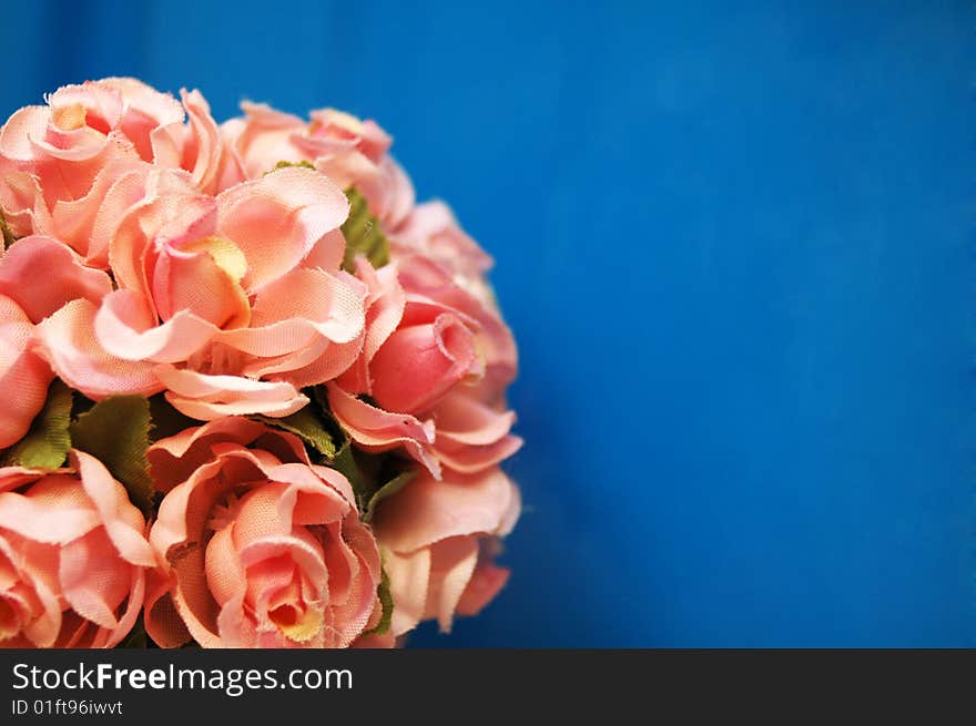 Fake pink flowers against blue background with a space for a text. Fake pink flowers against blue background with a space for a text