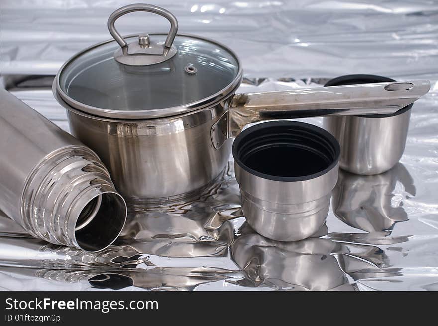 Metal pan and thermos against a foil. Metal pan and thermos against a foil.