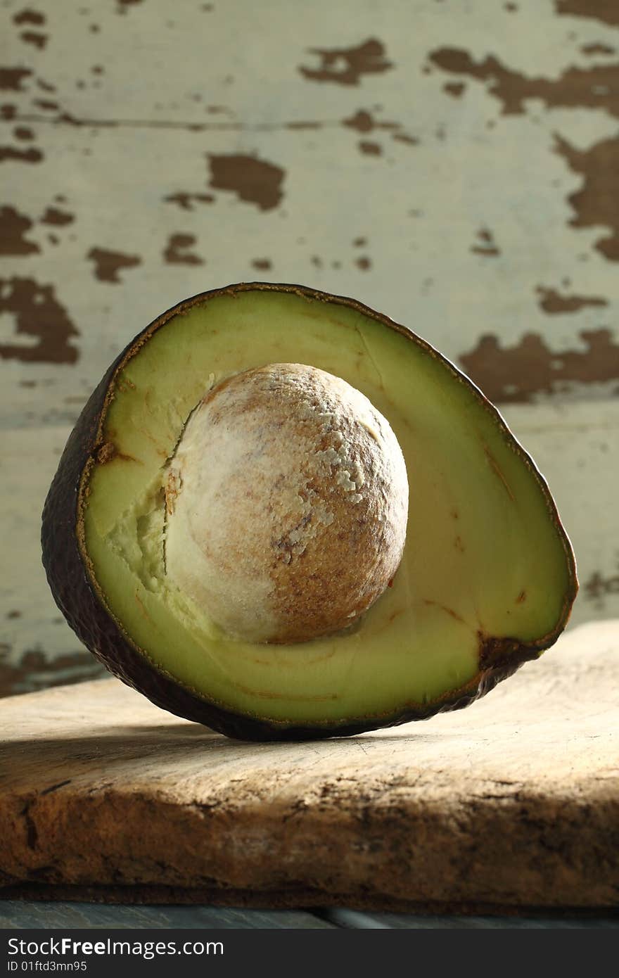 Sliced avocado, high vitamin E, big seed inside, on wooden plate. Sliced avocado, high vitamin E, big seed inside, on wooden plate.