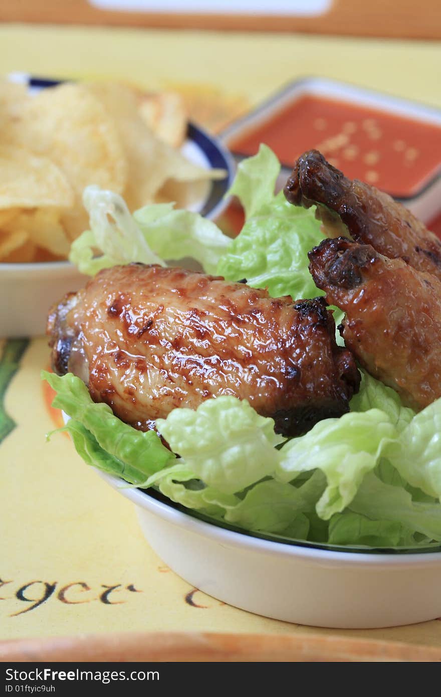 Grilled chicken wings with hot pepper sauce and salad