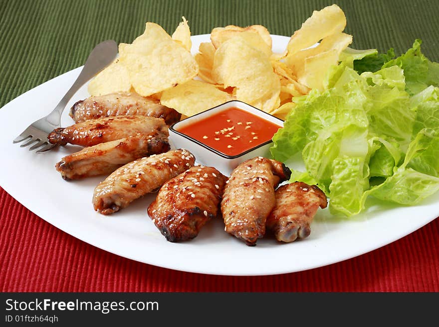 Grilled chicken wings with hot pepper sauce and salad