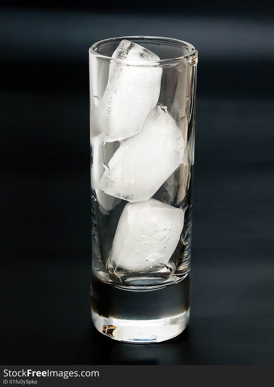 Transparent glass with ice bricks on the black background