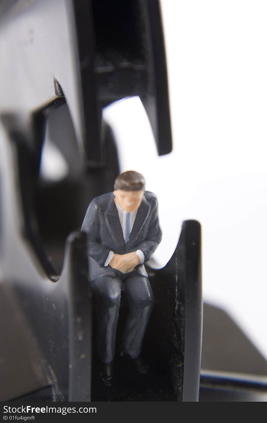 Miniature businessman sitting within a staple remover. Miniature businessman sitting within a staple remover.