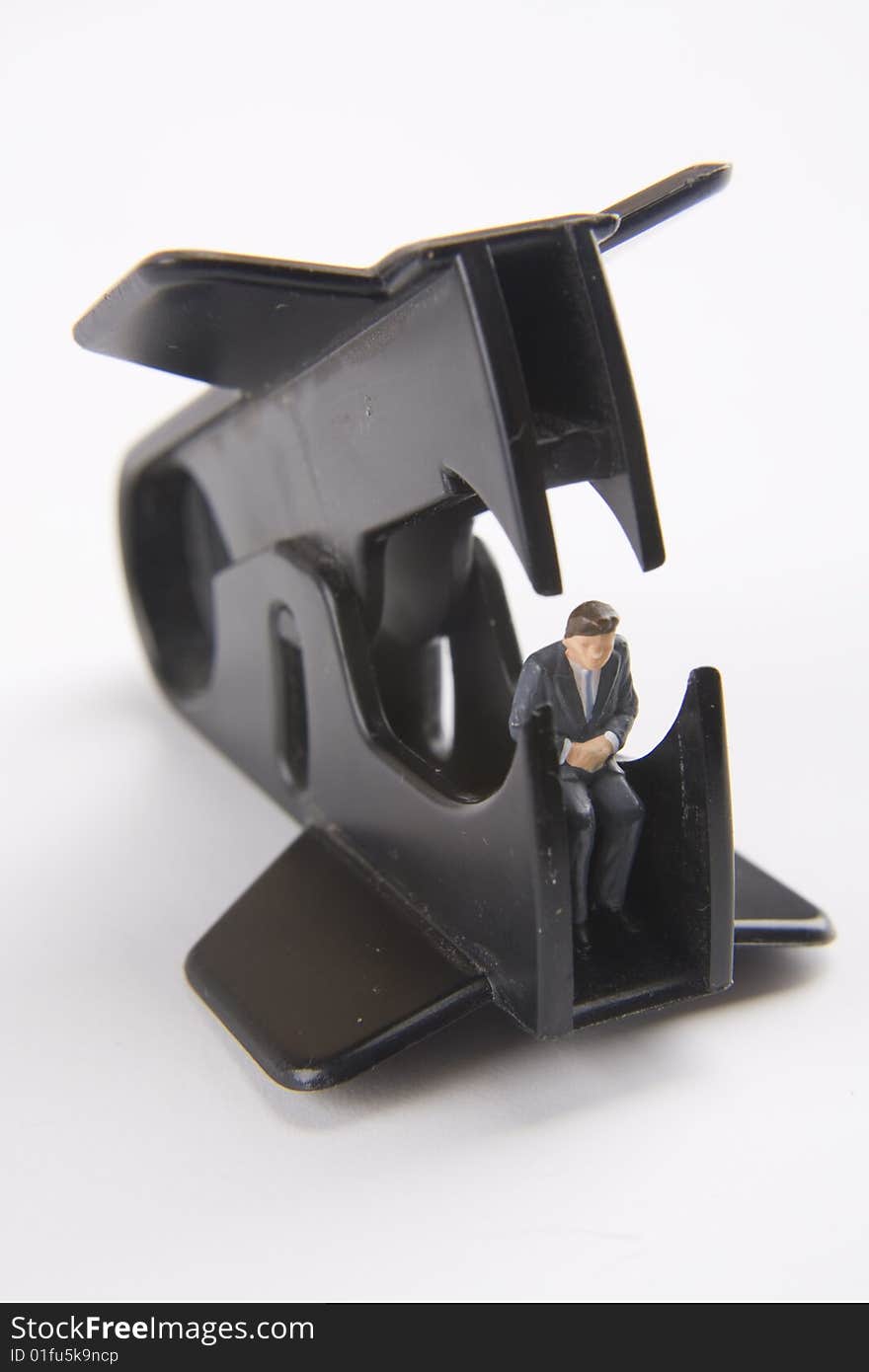 Miniature businessman sitting within a staple remover. Miniature businessman sitting within a staple remover.