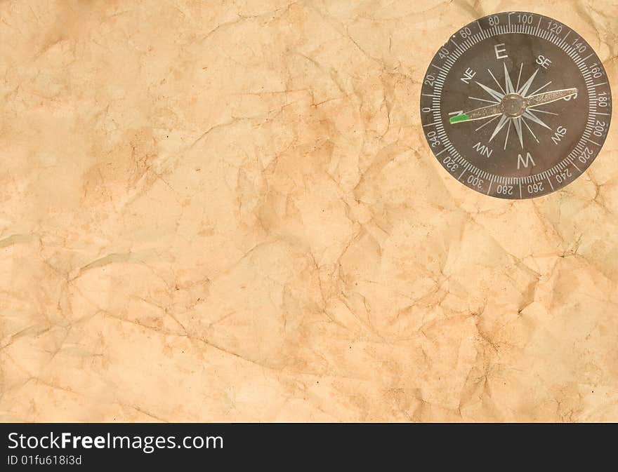 Old crumpled paper with a transparent compass in the corner. Old crumpled paper with a transparent compass in the corner