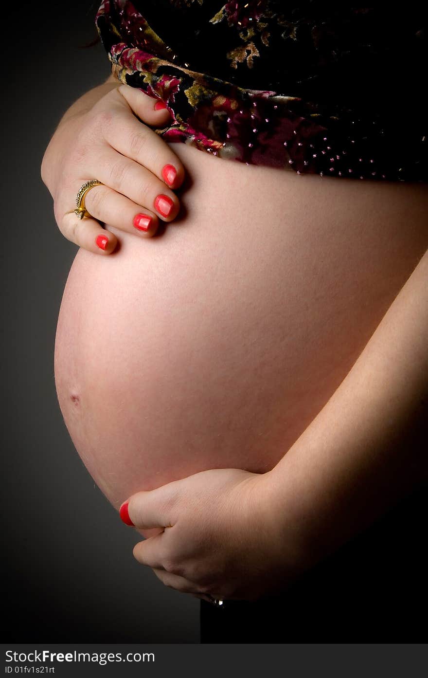 Side view of pregnant woman holding her tummy on an isolated background