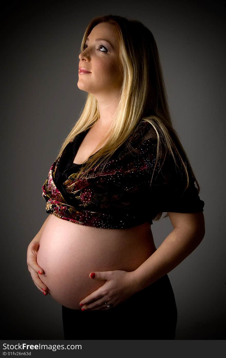 Side view of pregnant woman holding her tummy on an isolated background