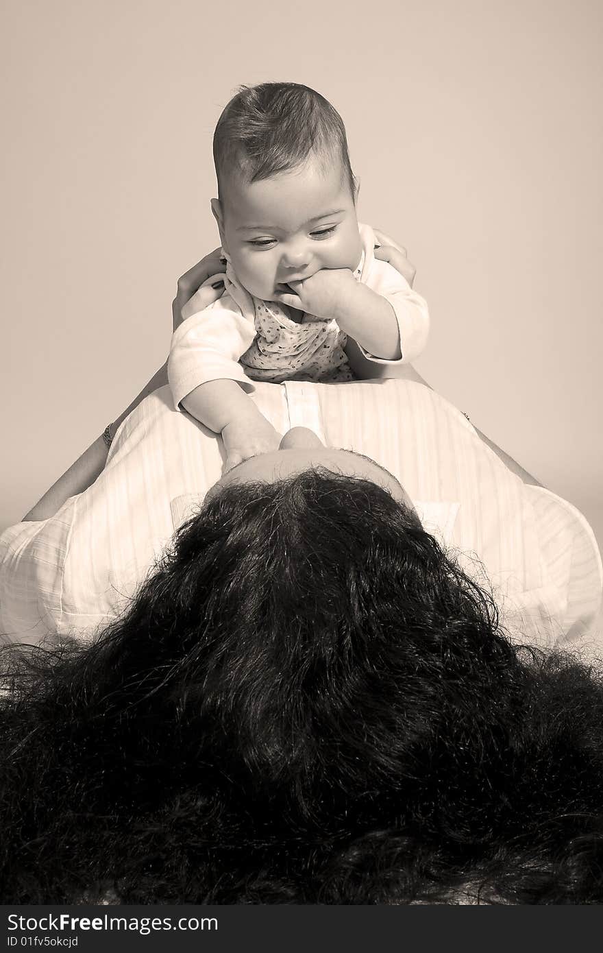 A baby that is sitting on top of her mother. A baby that is sitting on top of her mother