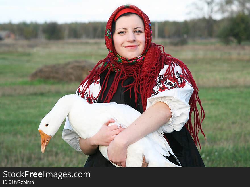 Village girl keeping a goose in Ukrainian clothes