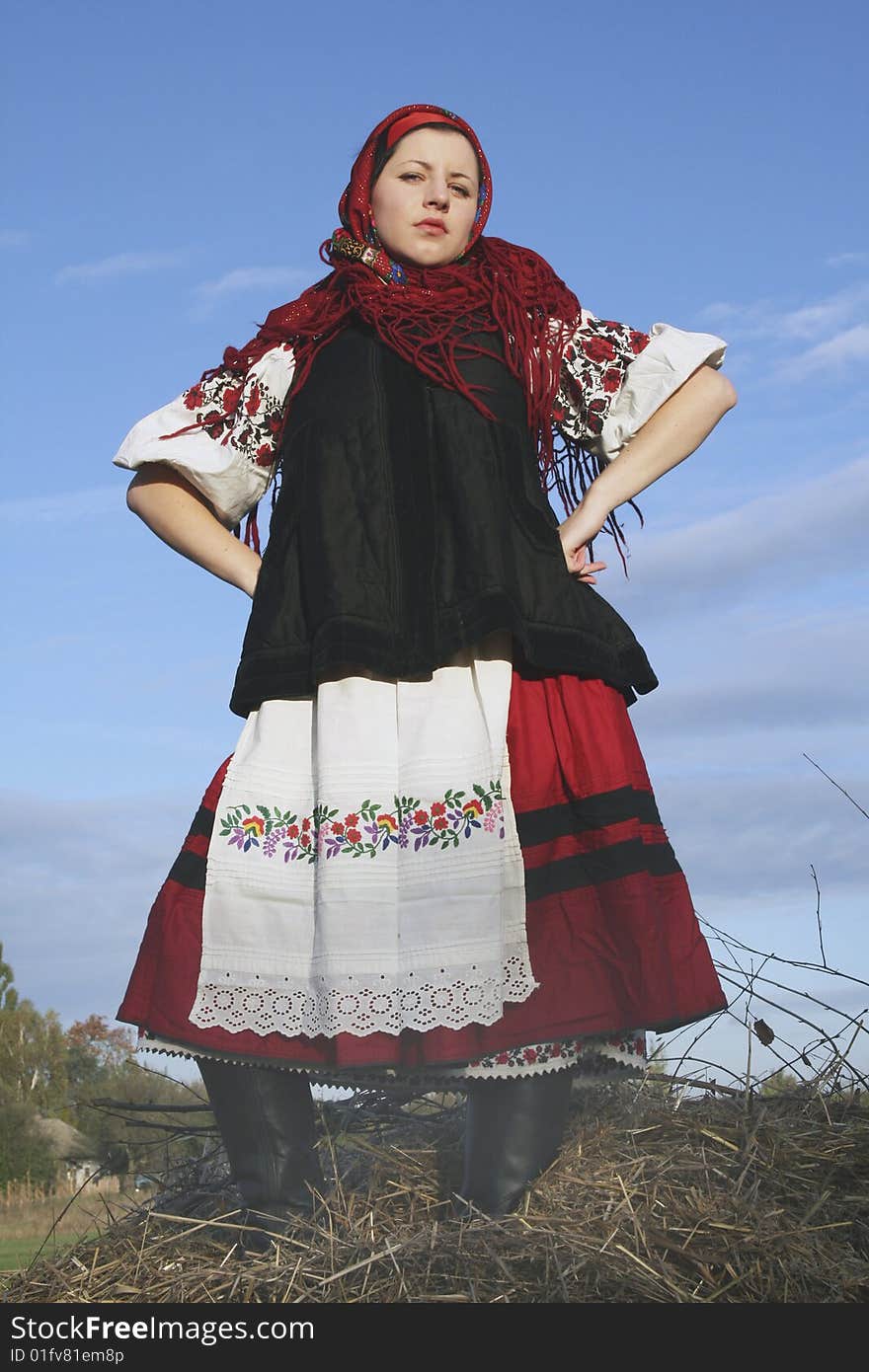 Village girl in Ukrainian clothes standing on haycock