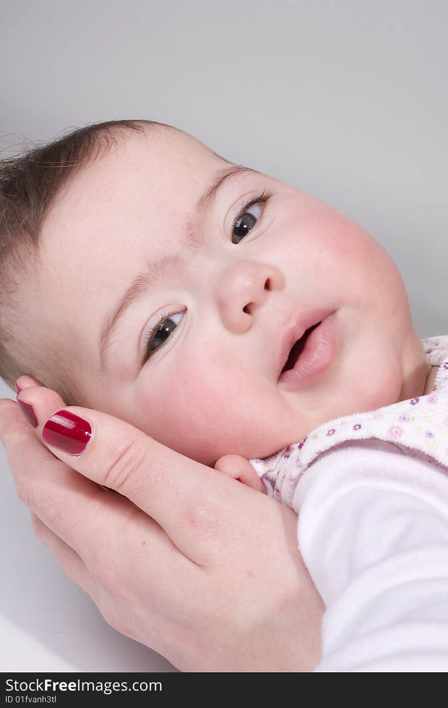 A baby girl that is being supported by the hand of her mother. A baby girl that is being supported by the hand of her mother