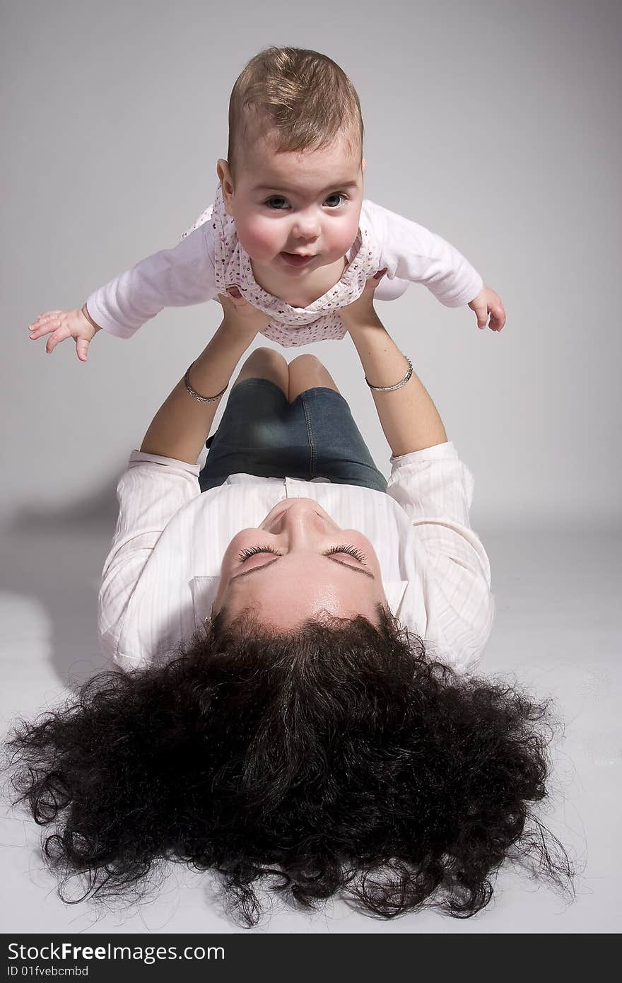 A mother holding her daughter up high as if it can fly. A mother holding her daughter up high as if it can fly