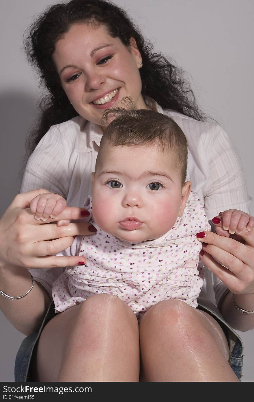 A baby on her mothers lap and being hold by her mother. Mom is looking very happy and proud. A baby on her mothers lap and being hold by her mother. Mom is looking very happy and proud.