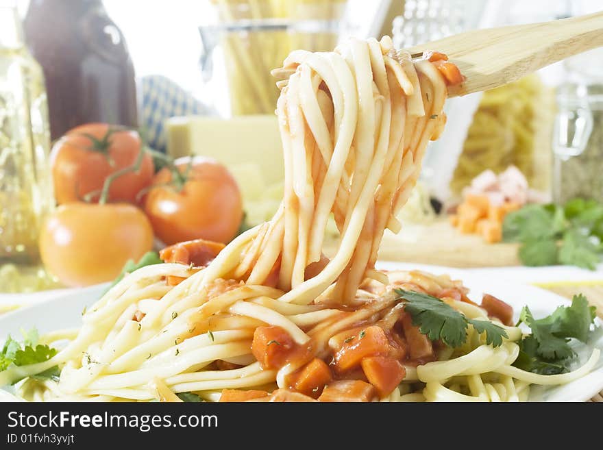 Freshly cooked spaghetti with tomato sauce on a wooden fork