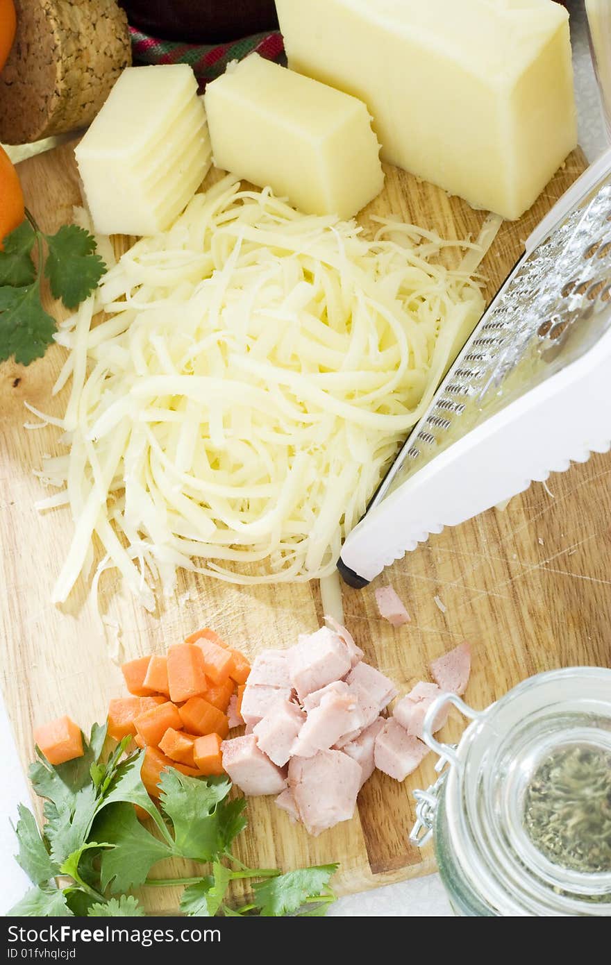 Overhead fresh grated cheese on wooden bread board