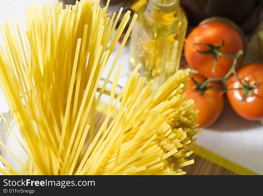 Overhead shot of raw spaghetti next to a tomatoes in glass container