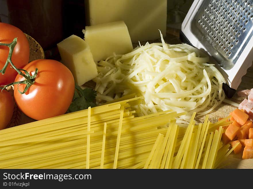 Overhead shot of raw spaghetti next to a tomatoes and grated cheese