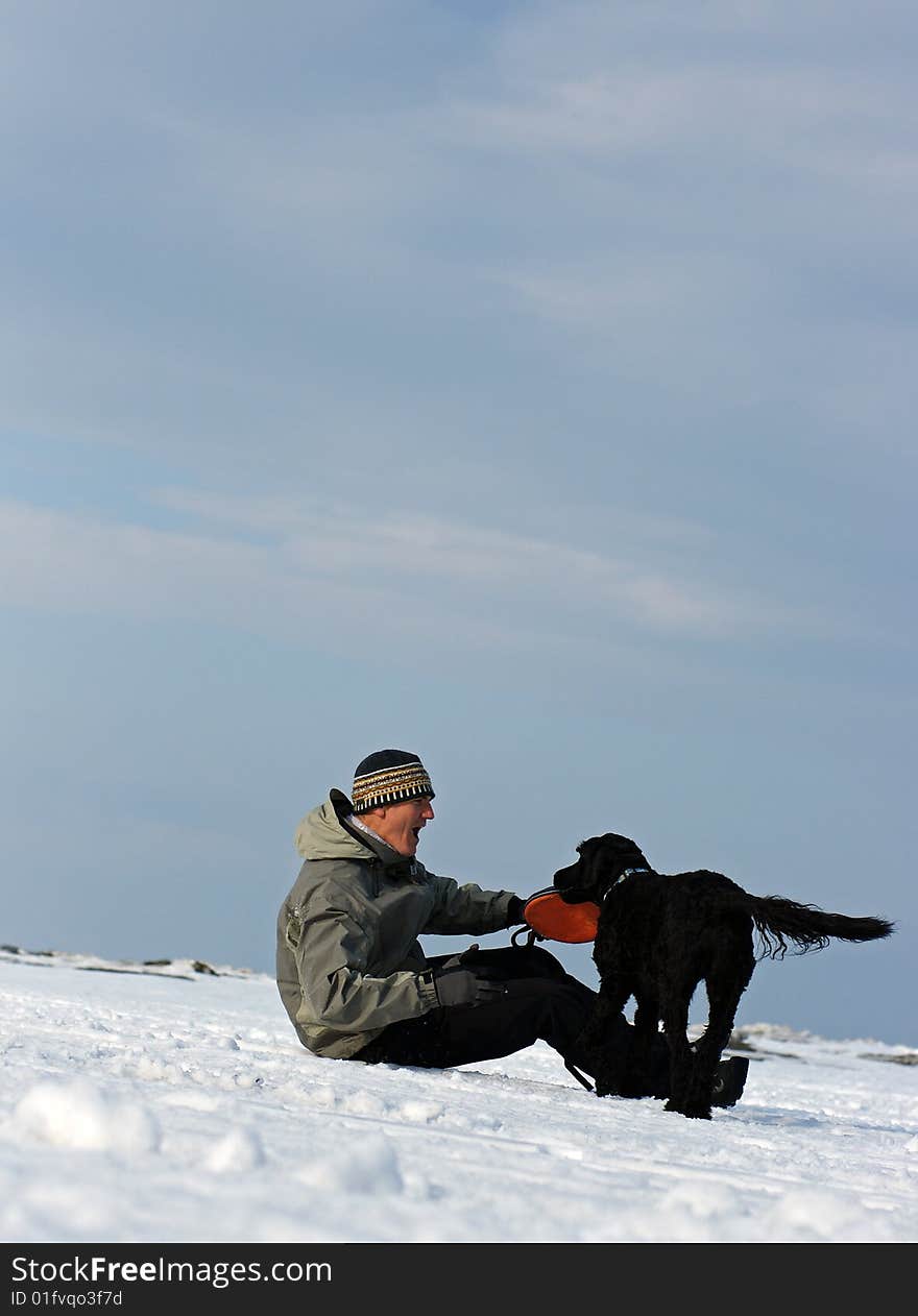 A Portuguese Water Dog retrieves a frisbee for his owner on the frozen shore of Georgian Bay, Ontario. A Portuguese Water Dog retrieves a frisbee for his owner on the frozen shore of Georgian Bay, Ontario