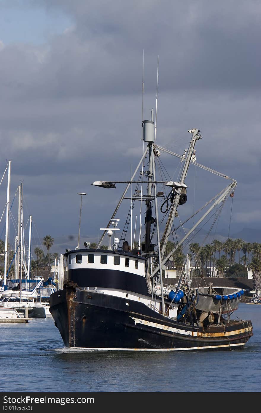 A black and white fishing boat leaving the harbor and dark storm clouds in the sky. A black and white fishing boat leaving the harbor and dark storm clouds in the sky.