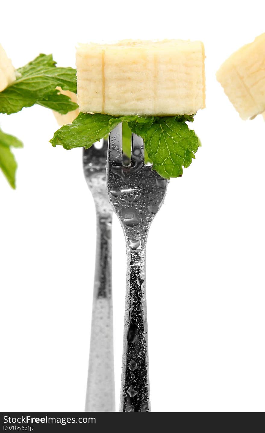 Slices of fresh banana and mint leaves on forks over white. Slices of fresh banana and mint leaves on forks over white.