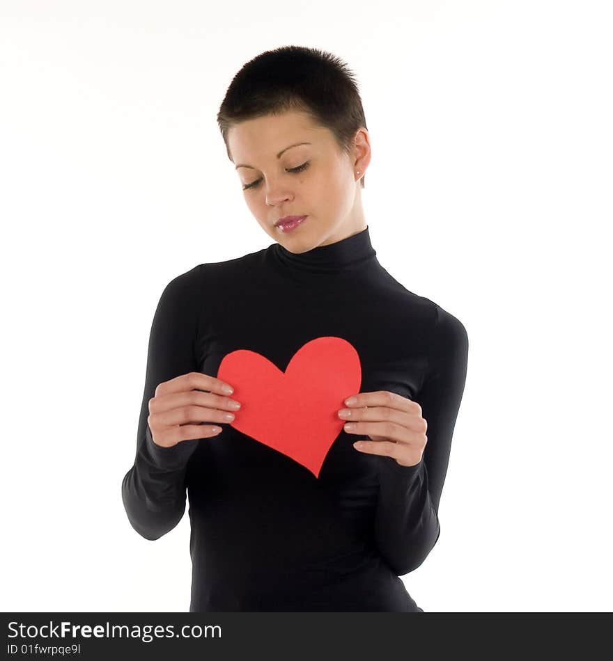 A short hair slim brunette in black dress holds a red paper heart. A short hair slim brunette in black dress holds a red paper heart