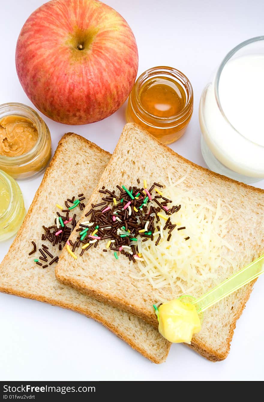 Meal ingredient for healthy & easy breakfast: wheat bread, fruit jam, chocolate sprinkles, a glass of milk, butter and apple. Meal ingredient for healthy & easy breakfast: wheat bread, fruit jam, chocolate sprinkles, a glass of milk, butter and apple