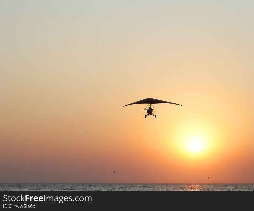 Hangglider In Action Against A Sea Sunset