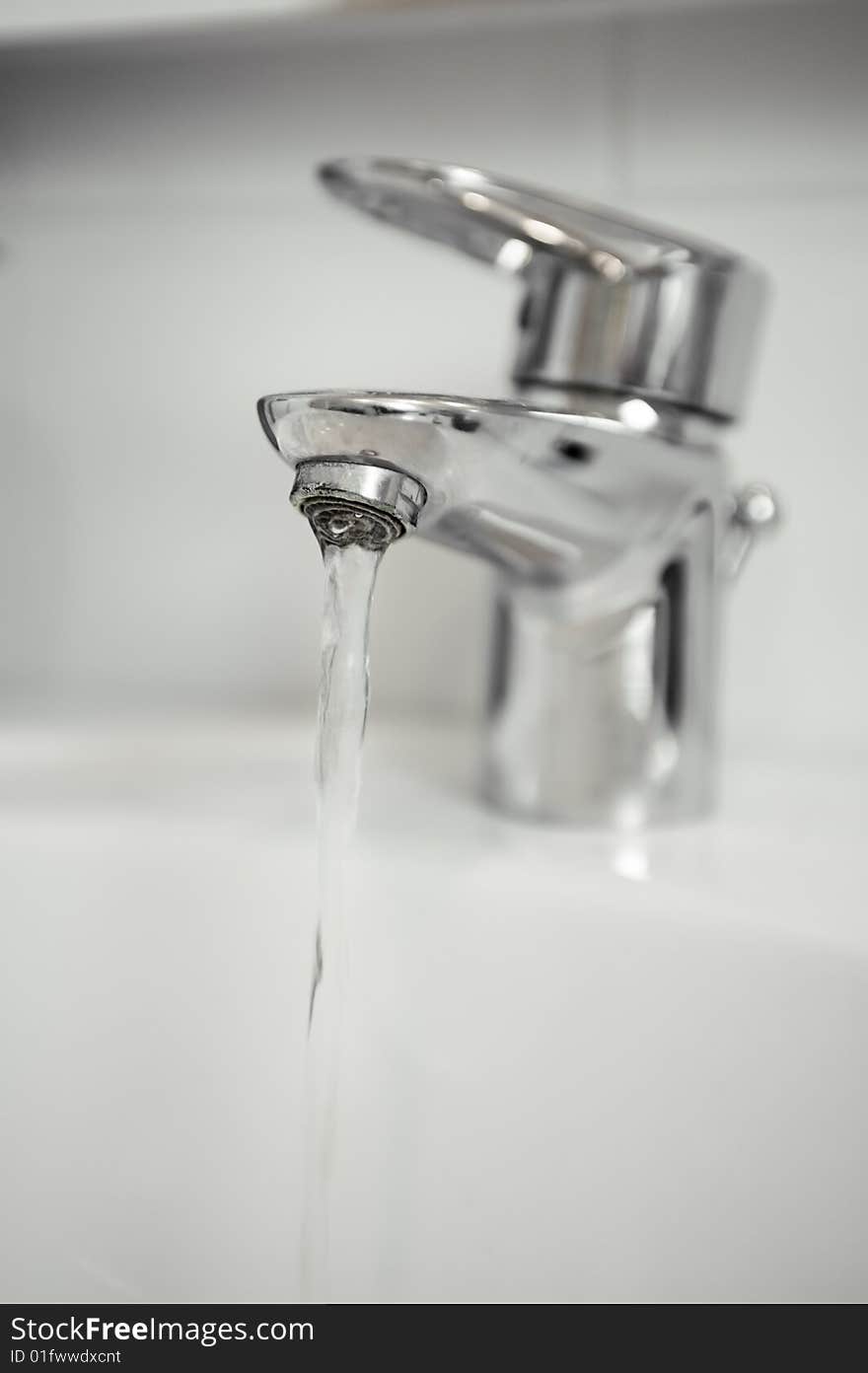 Water tap with focus on water coming out of tap. Portret orientation.