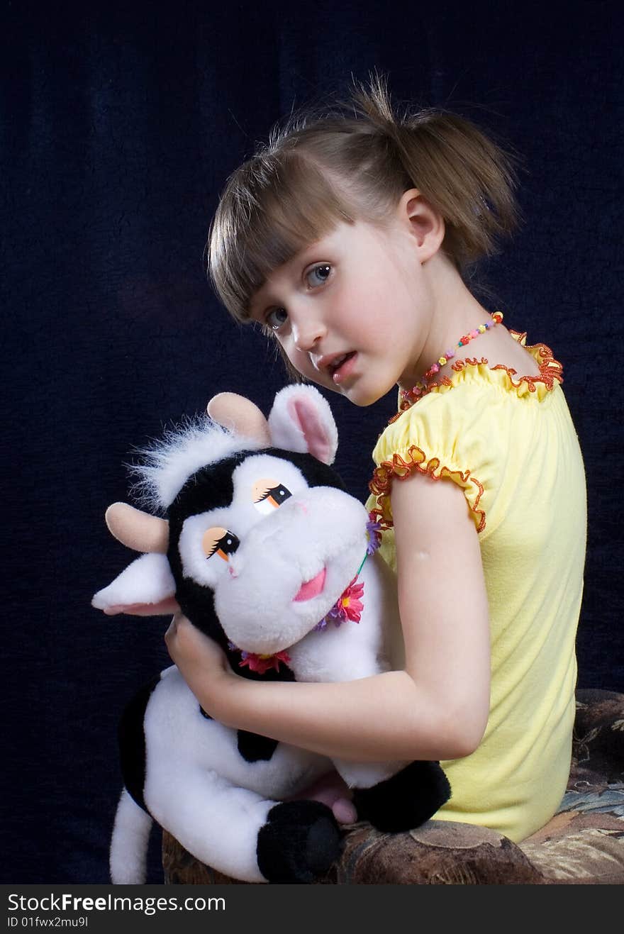 Girl sits on chair in hand toy(cow). Girl sits on chair in hand toy(cow)