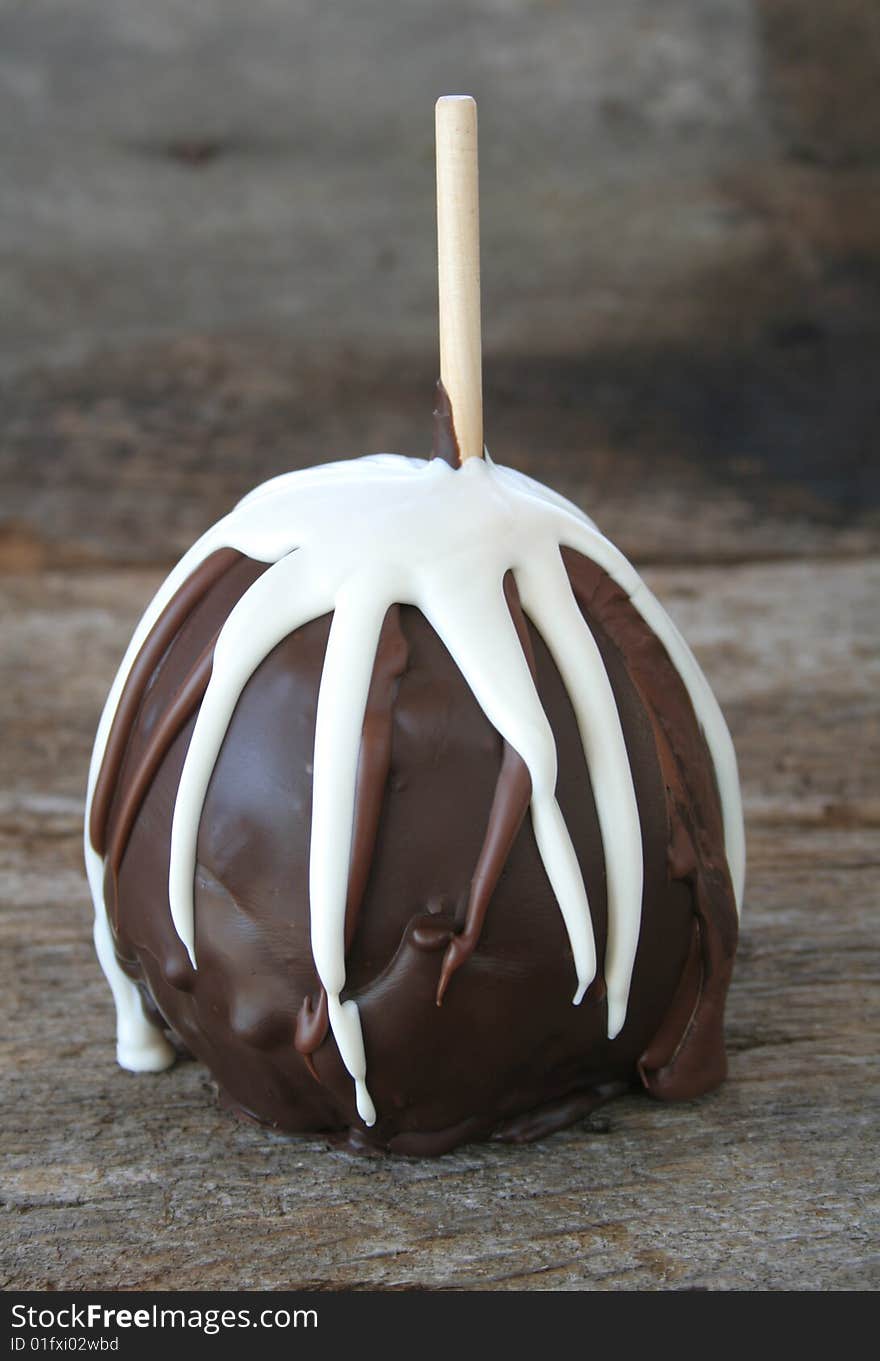 An apple dipped in dark and white chocolate on a wooden background for a rustic look. An apple dipped in dark and white chocolate on a wooden background for a rustic look.