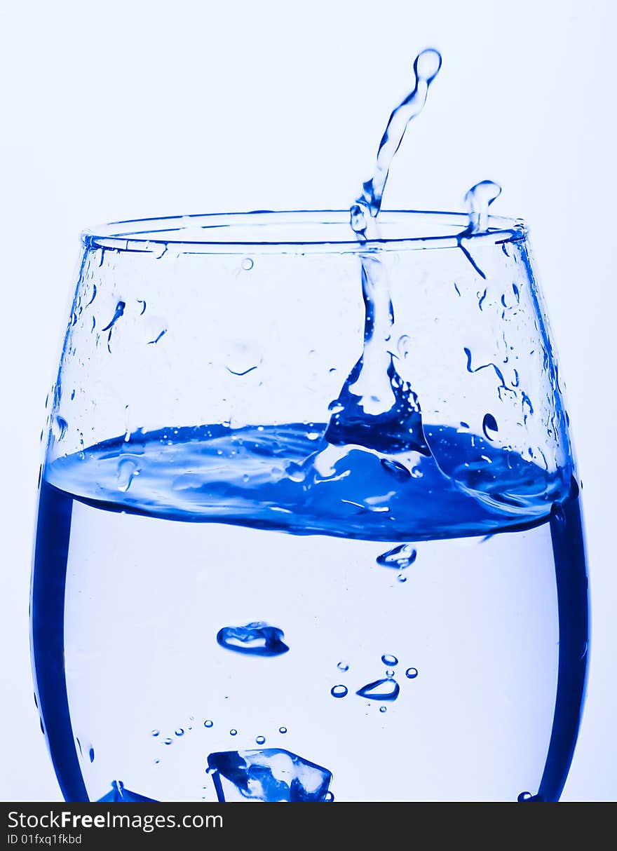 Blue Glass with Splashing water. Coolness Drink