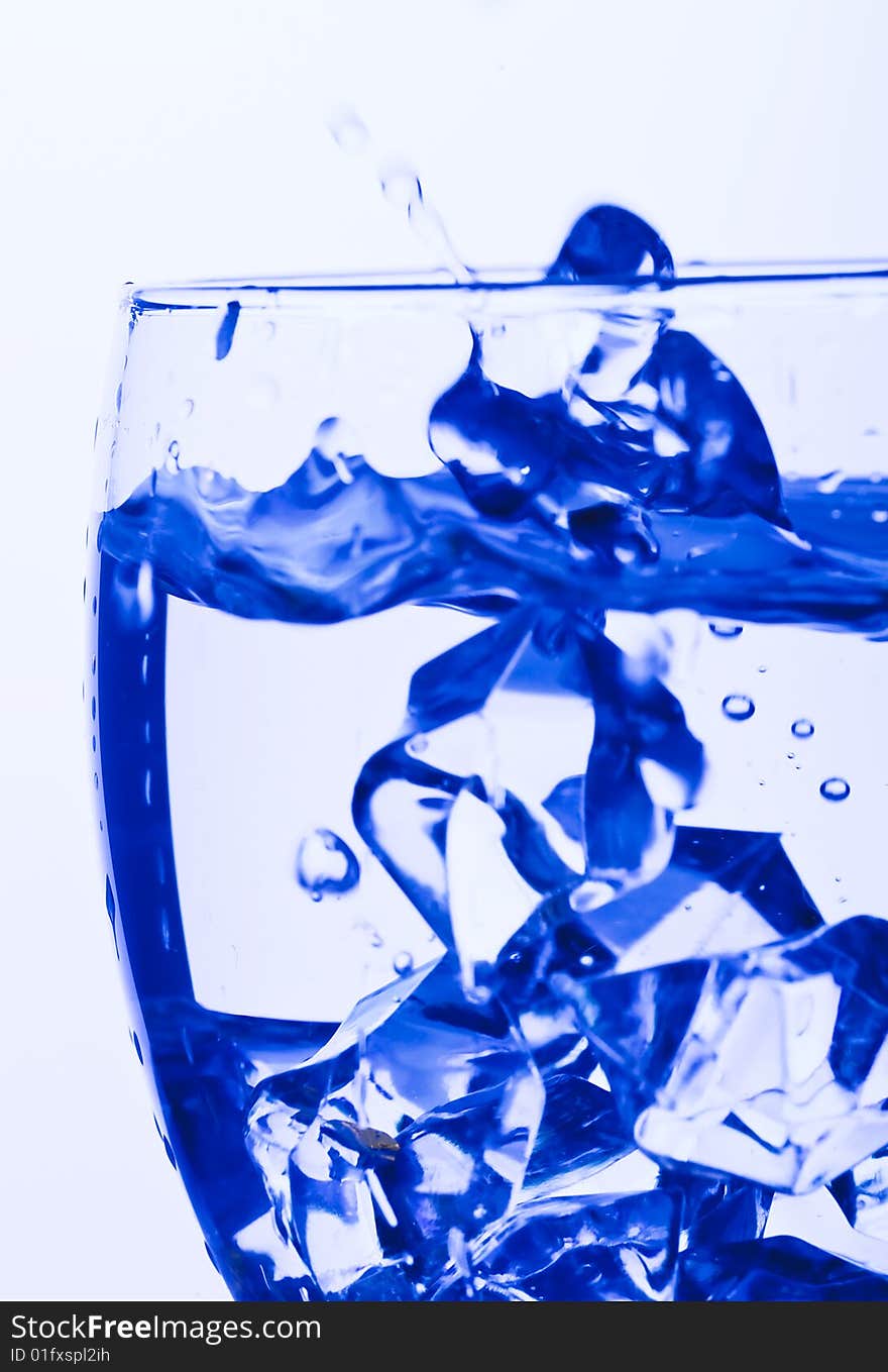 Blue Glass with Splashing water. Coolness Drink