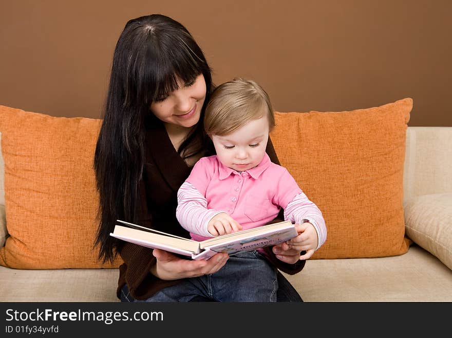 Mother and daughter reading book on sofa