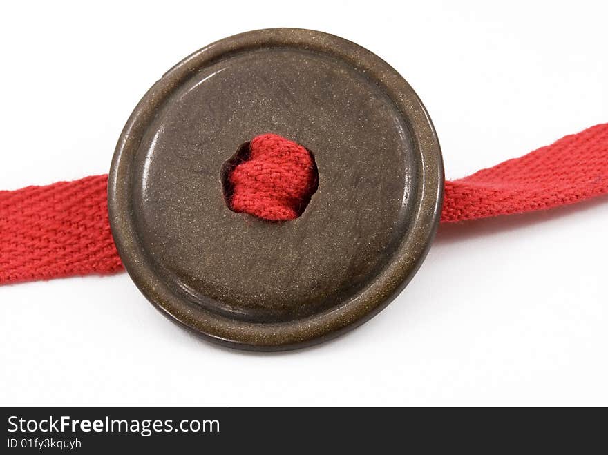 Brown button with a red ribbon on white background. Brown button with a red ribbon on white background