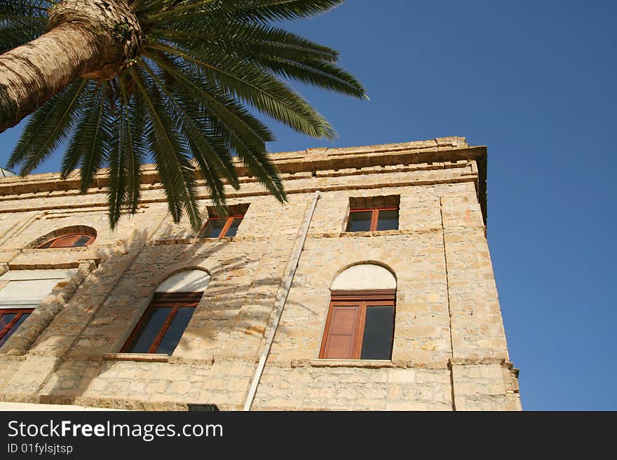 Palm and ancient house with a blue sky